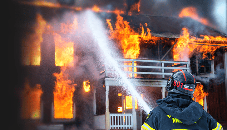 Fireman pouring water on a house fire with a hosepipe