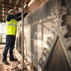 Contractor with helmet and vest repairing damaged wall
